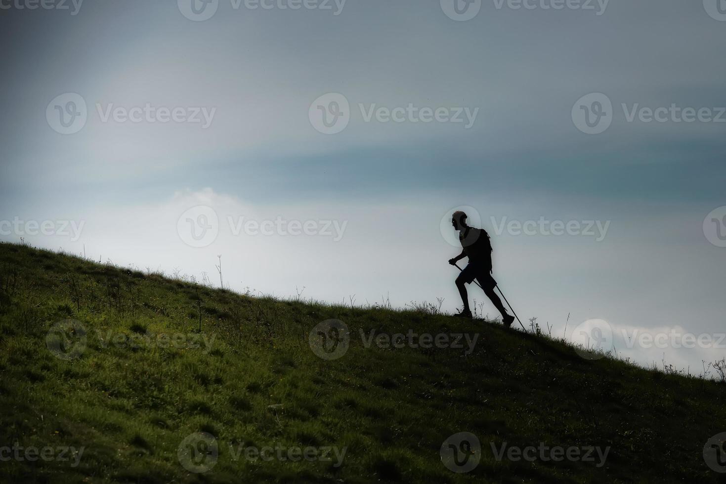 Nordic walking uphill on a hilly meadow in silhouette photo