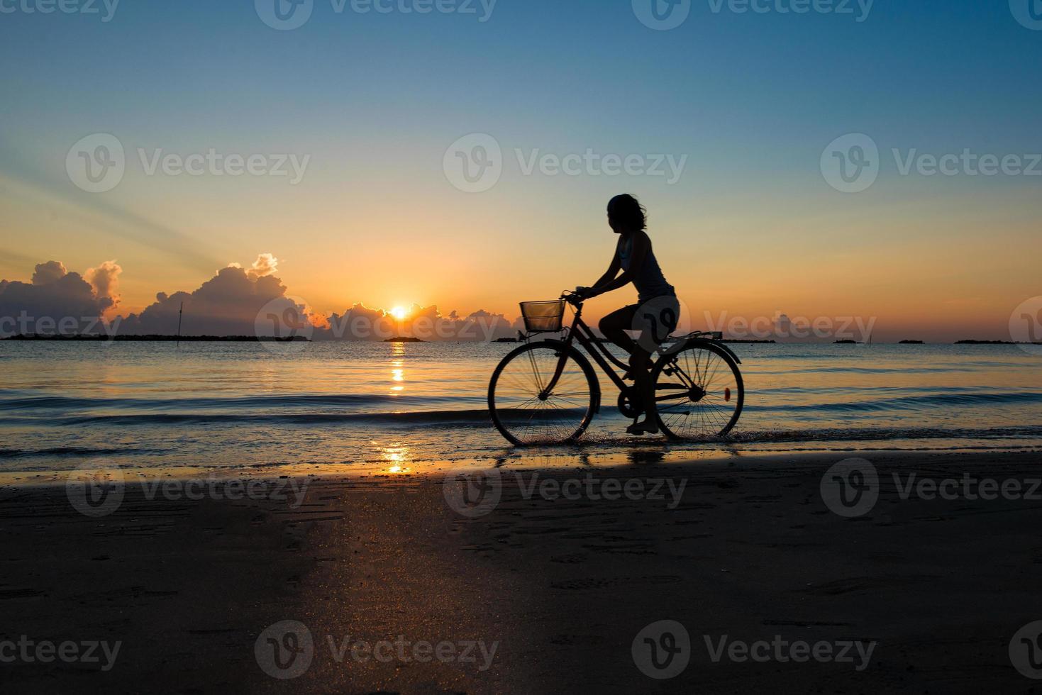 Girl cycling in the sea during sunrise photo
