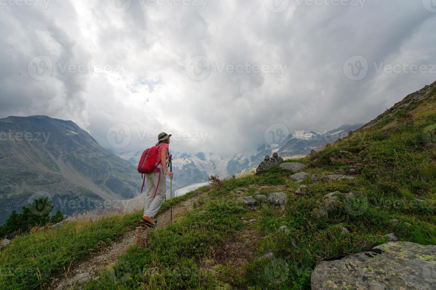 Retired woman practices a hike in the high mountains photo