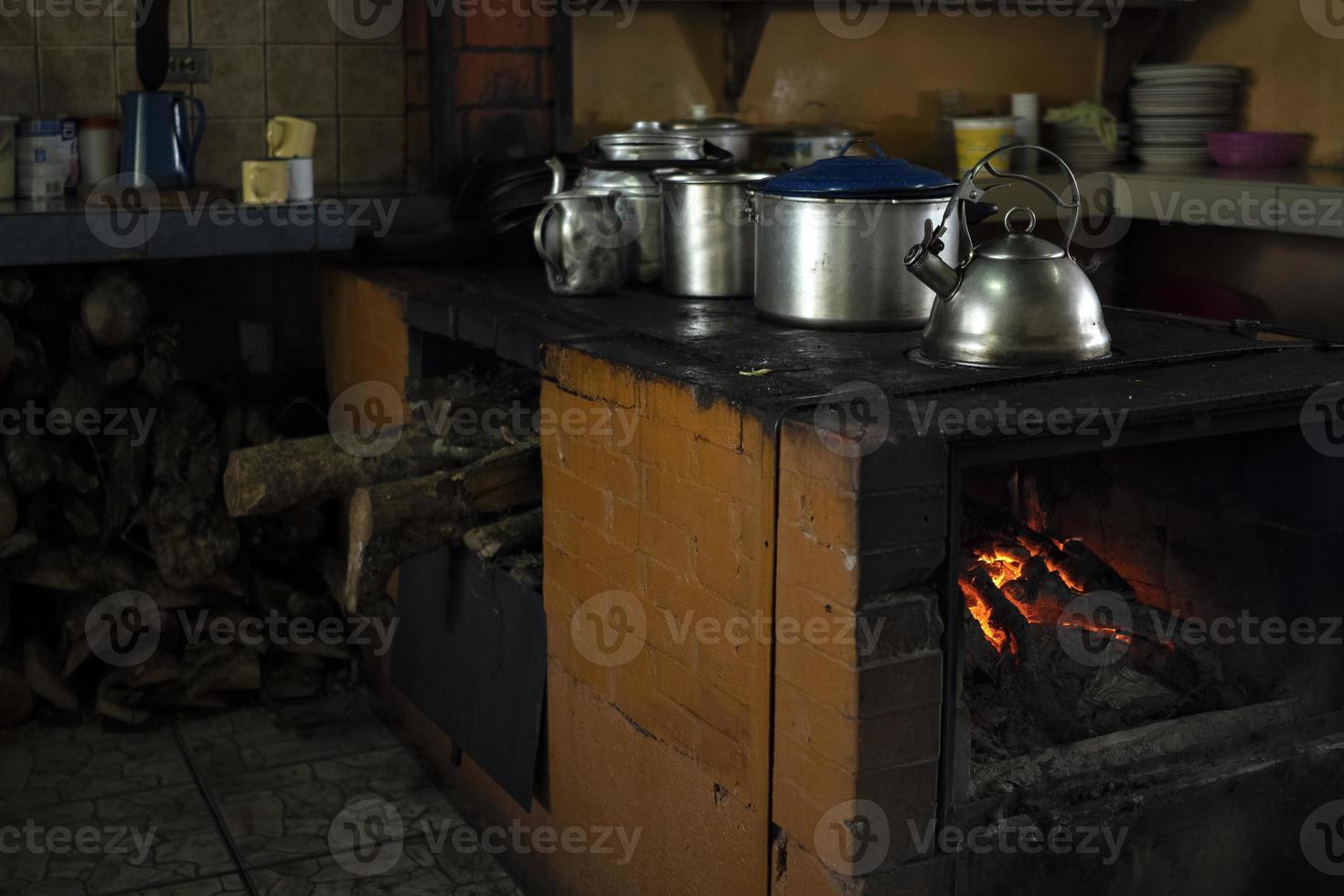 Traditional kitchen with wood stove burning and metal pots and pans. photo