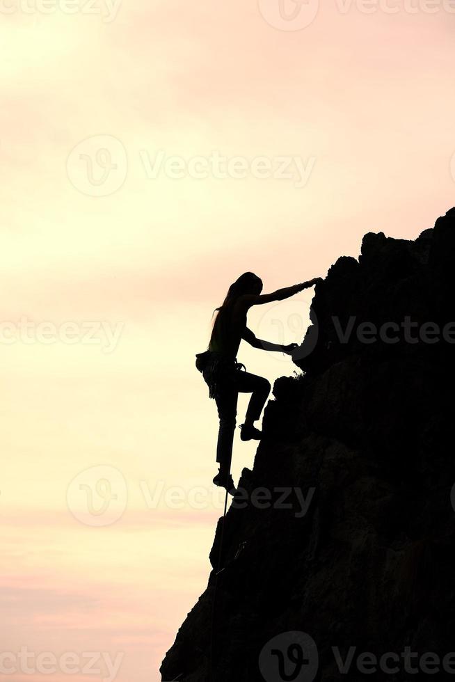 Girl alone conquer the summit during a climb in a fantastic mountain landscape at sunset photo