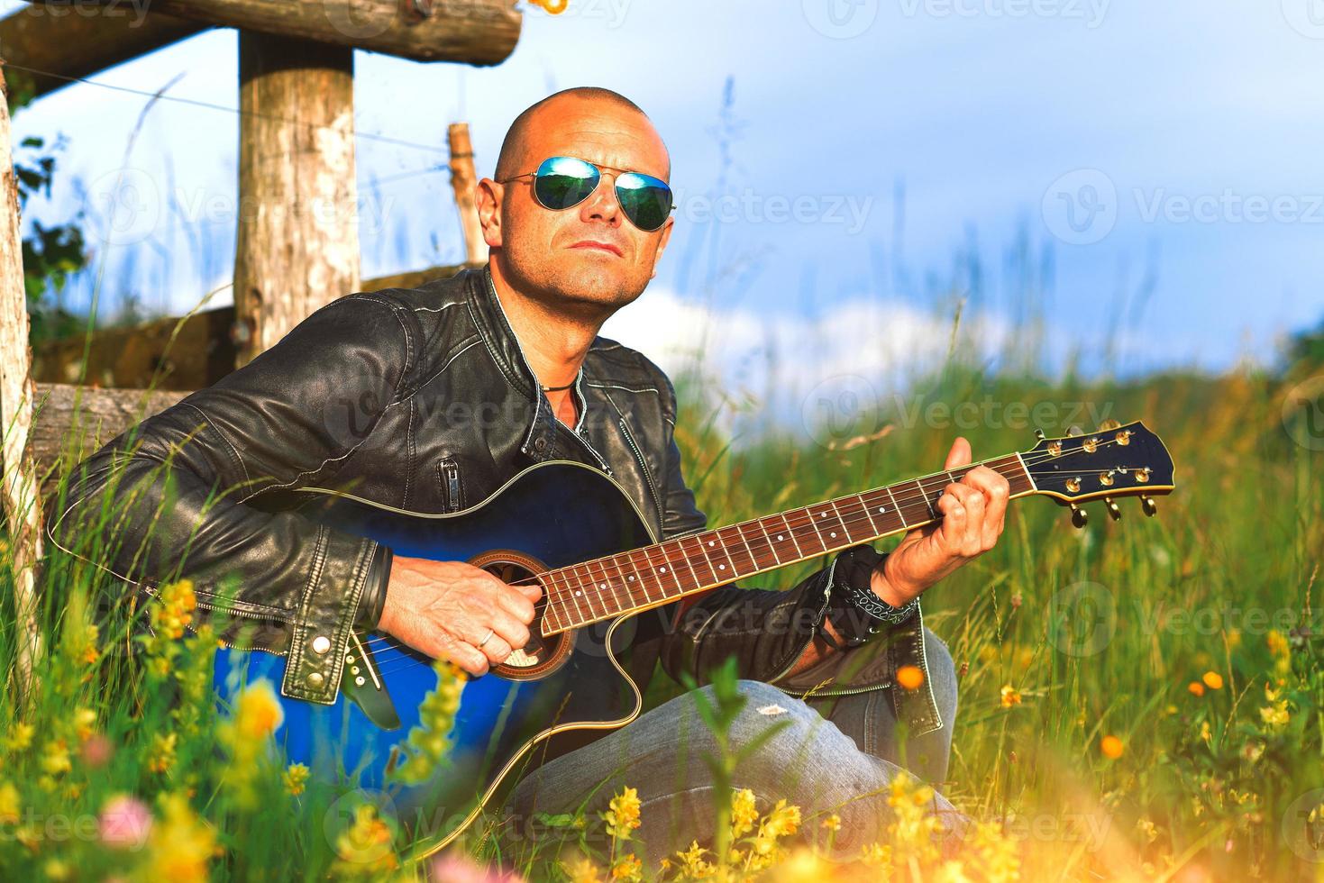 cantante con guitarra toca solo en un prado en la naturaleza foto