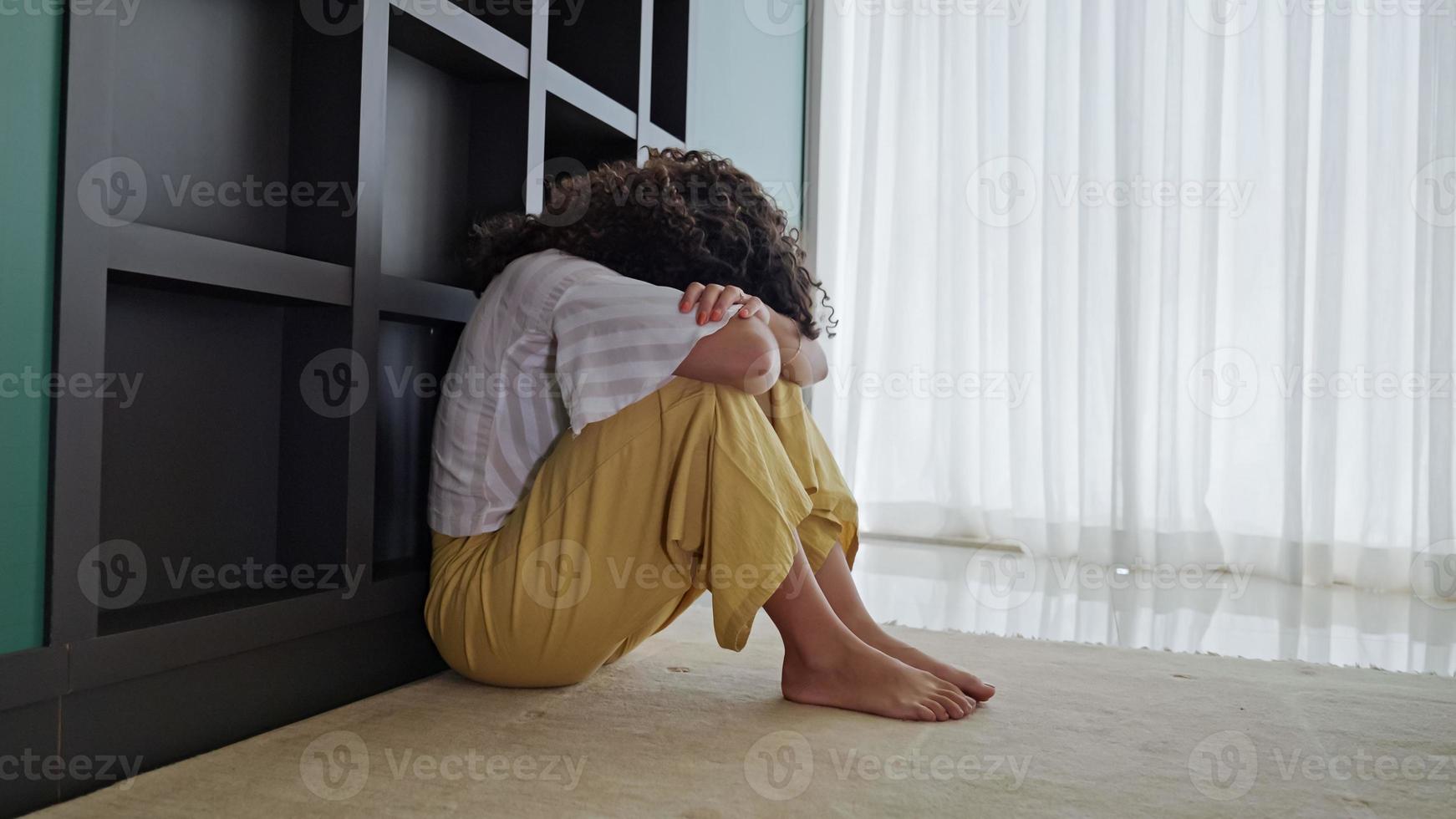 Latin woman sitting on floor feels unhappy by personal problems, break up or ruined marriage photo