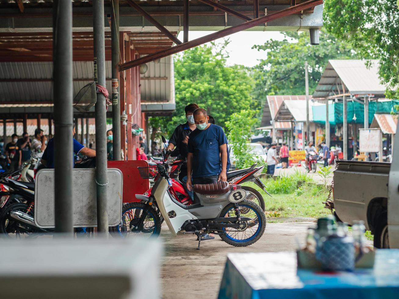 Chiang Mai, Thailand, 2021 A middle-aged Asian man stands earnestly looking at an old motorcycle. photo
