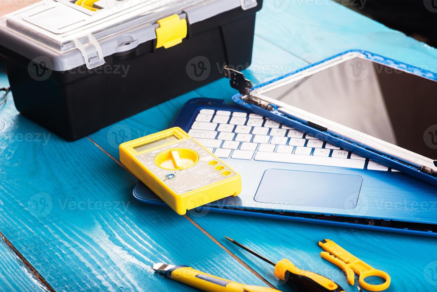 Wizard repairs laptop with tools and hands on the blue wooding table. top view photo