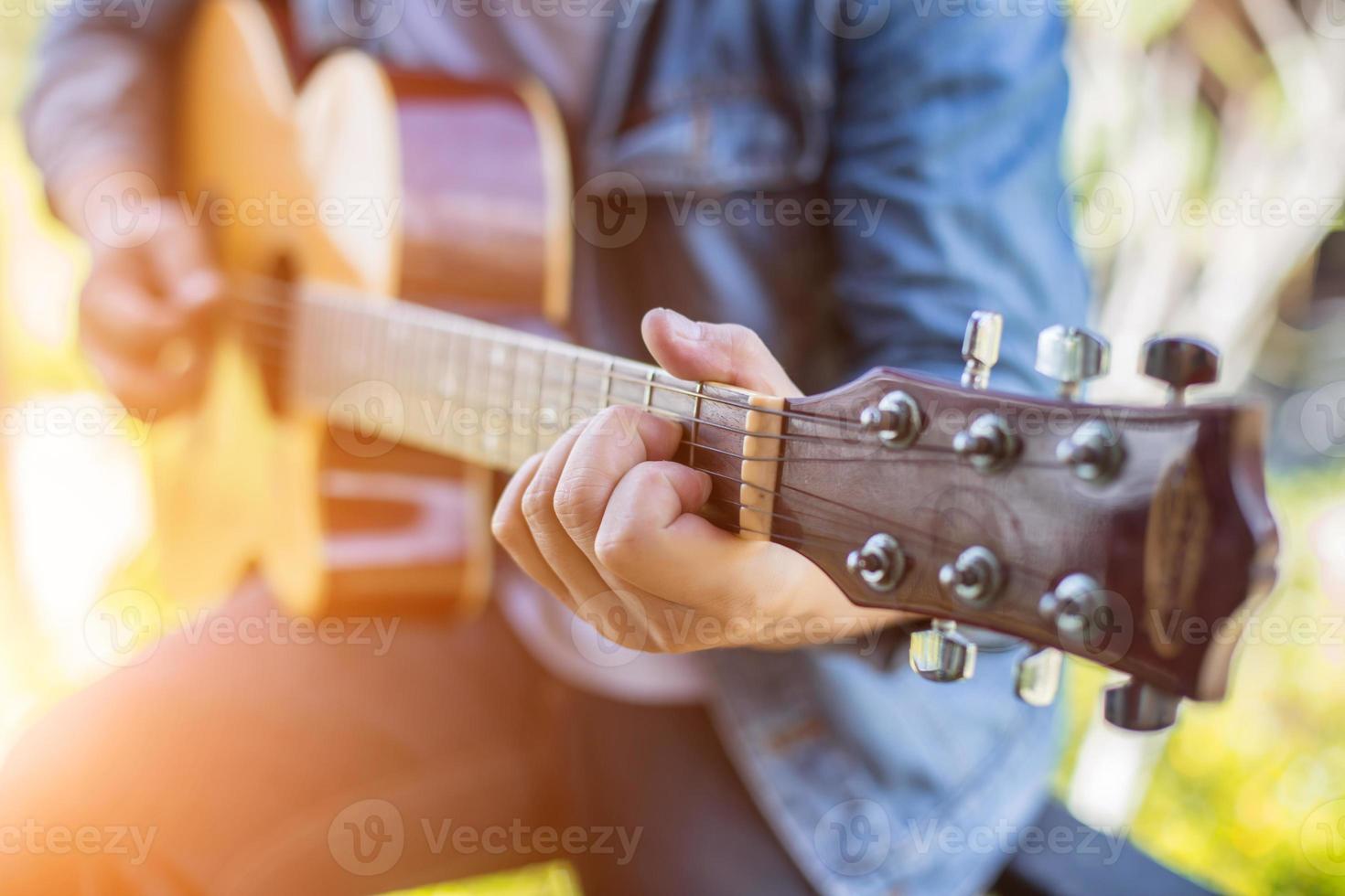 joven hipster tocando guitarra para relajarse en sus vacaciones, disfrutar con aire fresco y natural. foto