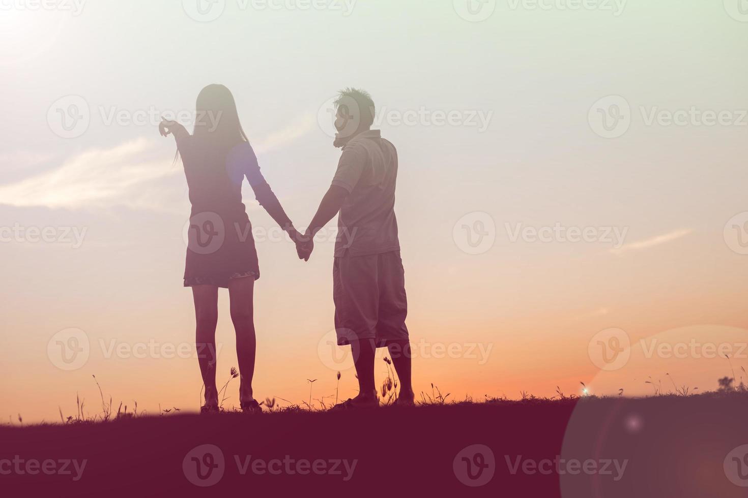 silhouette of a man and woman holding hands with each other, walking together. photo