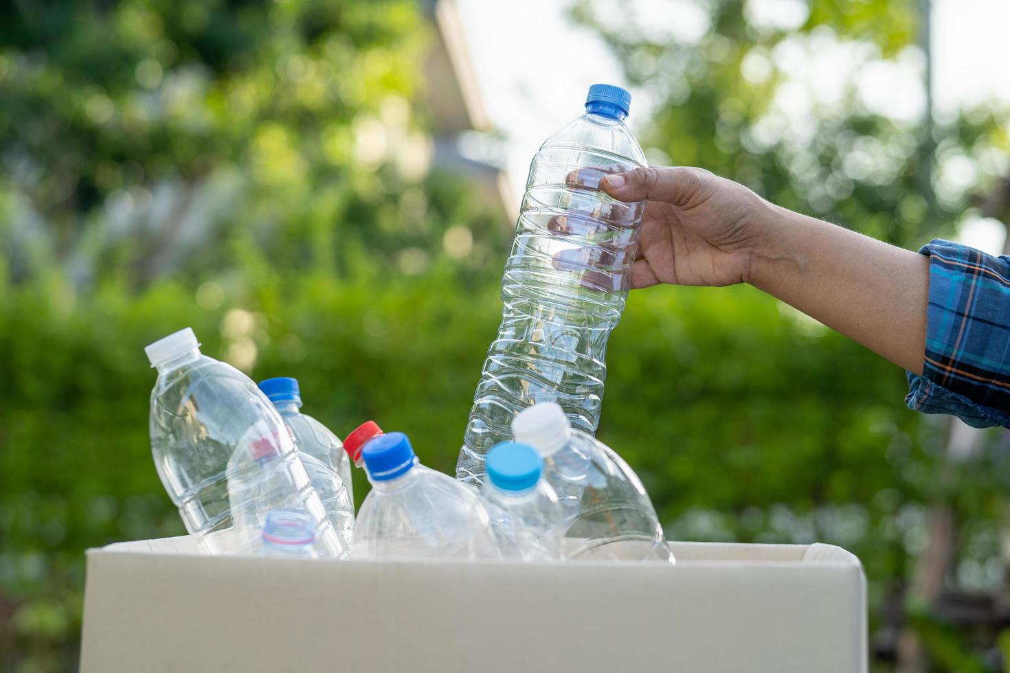 Asian woman volunteer carry water plastic bottles into garbage box trash in park, recycle waste environment ecology concept. photo