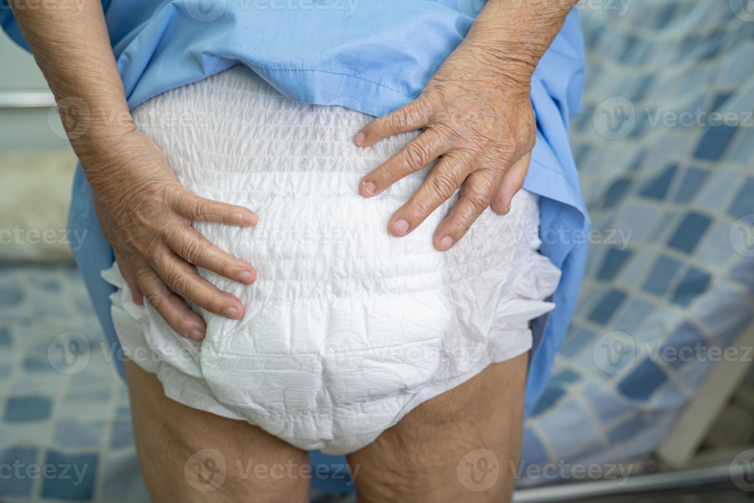 Paciente asiático mayor o mayor de la mujer de la señora mayor que lleva el pañal de la incontinencia en la sala del hospital de enfermería, concepto médico fuerte sano. foto