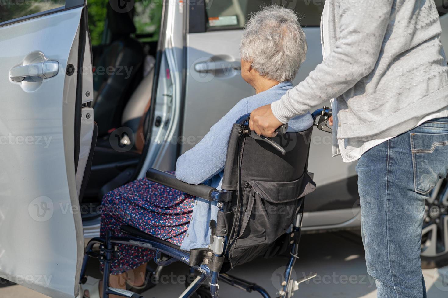 Help and support asian senior or elderly old lady woman patient sitting on wheelchair prepare get to her car, healthy strong medical concept. photo