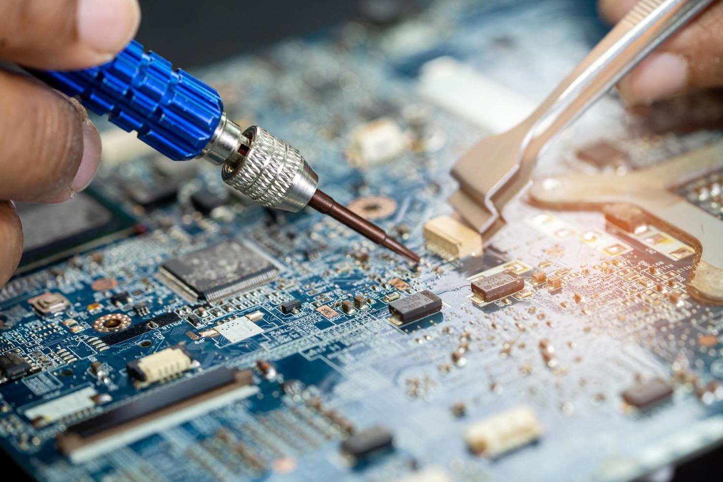 Technician repairing inside of printed circuit board PCB by soldering iron. Integrated Circuit. the concept of data, hardware, technician and technology. photo