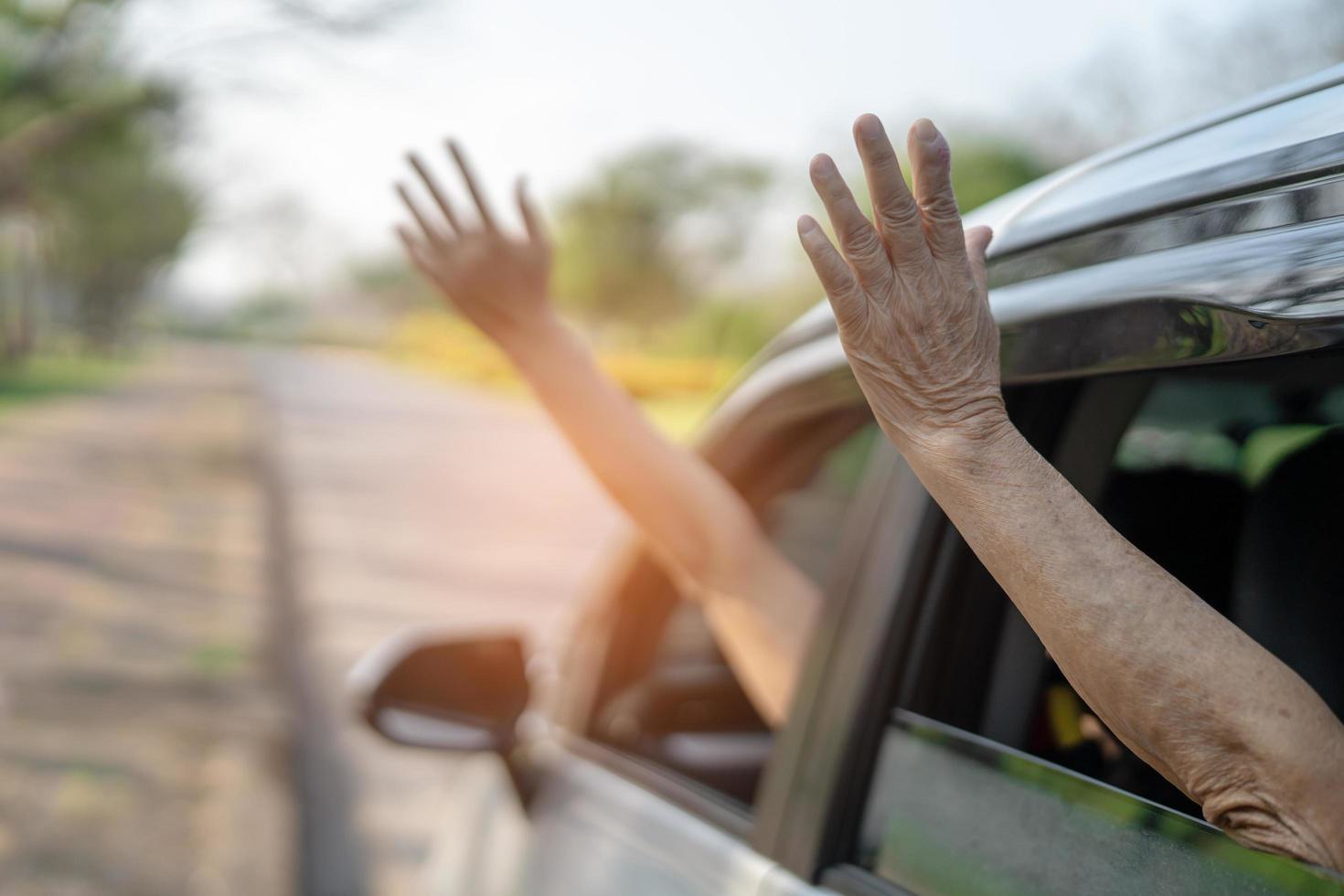 feliz disfrute y libertad en el viaje de viaje con la mano de la madre levantada fuera del coche de la ventana en las vacaciones de verano foto