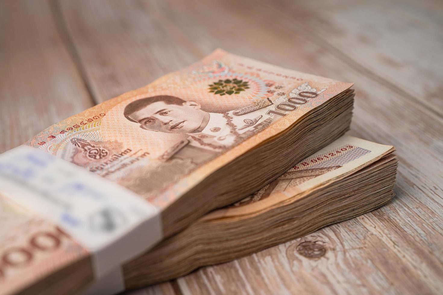 Stack of Thai baht banknotes on wooden background, business saving finance investment concept. photo