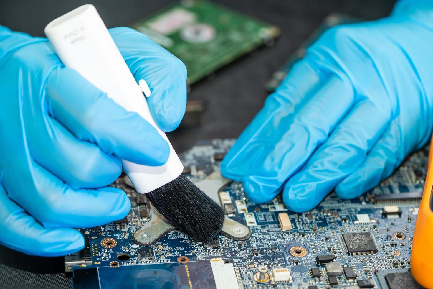 El técnico usa un cepillo y una bola de aire para limpiar el polvo en la placa de circuito de la computadora. reparación de tecnología de actualización y mantenimiento. foto