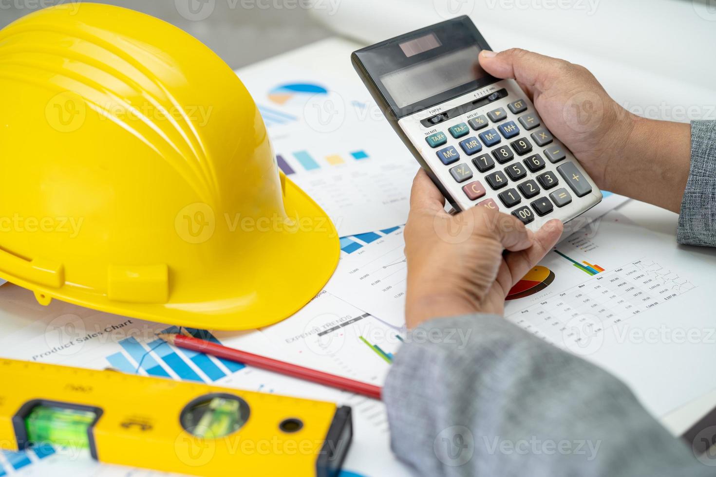 Asian engineer with architectural house plan project blueprint, graph and yellow helmet and engineering construction tools. photo