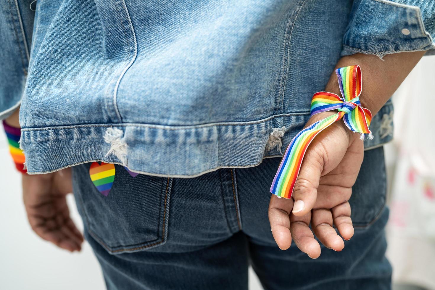 dama asiática con pulseras de la bandera del arco iris, símbolo del mes del orgullo lgbt celebran anualmente en junio las redes sociales de gays, lesbianas, bisexuales, transgénero, derechos humanos. foto