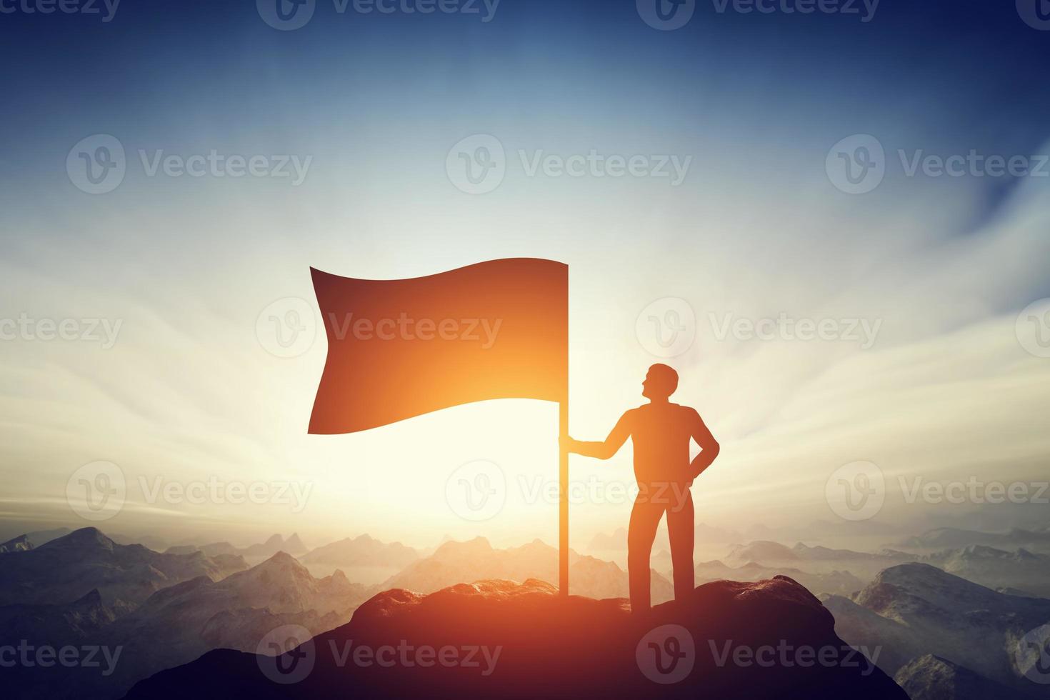 Proud man raising a flag on the peak of the mountain. Challenge, achievement photo
