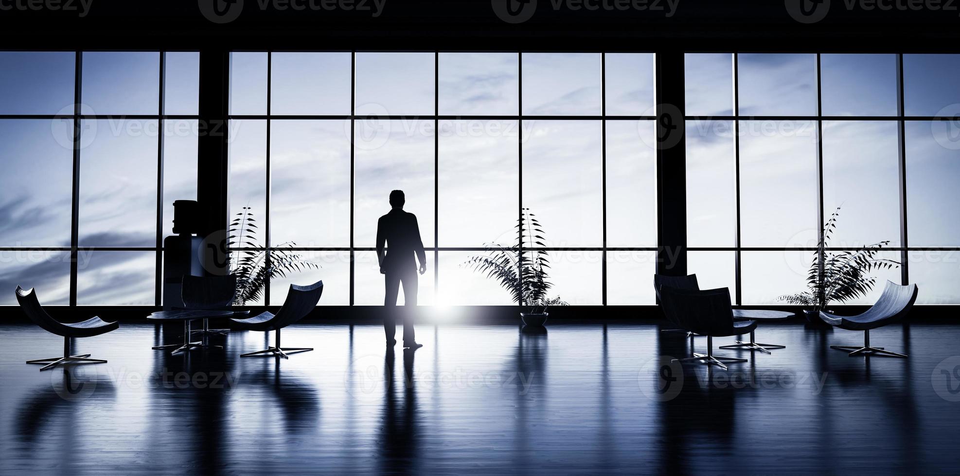 Business man standing in the office looking out of the window at sunset sky. photo