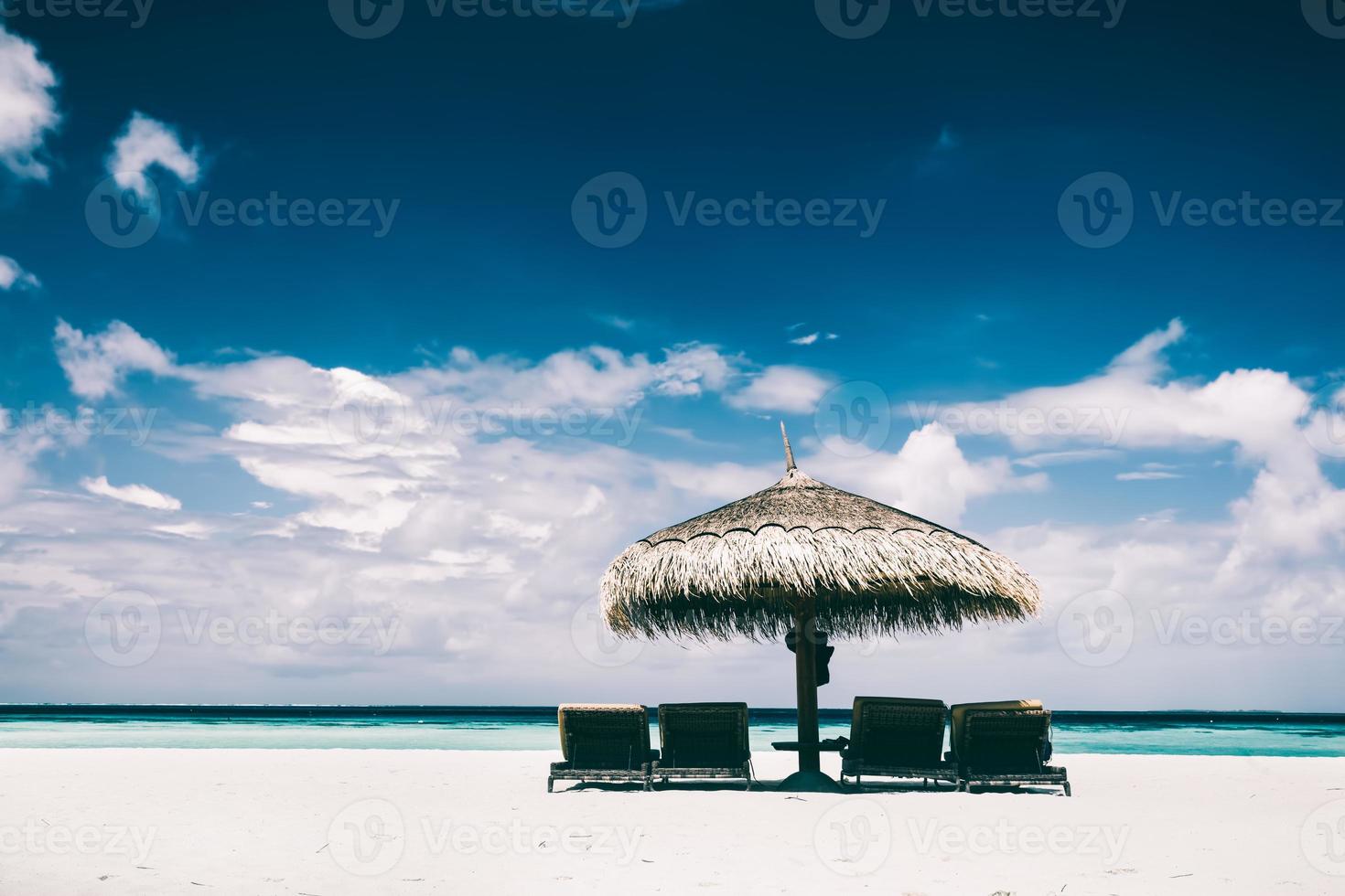 Straw umbrella and sunbeds on a sandy beach photo