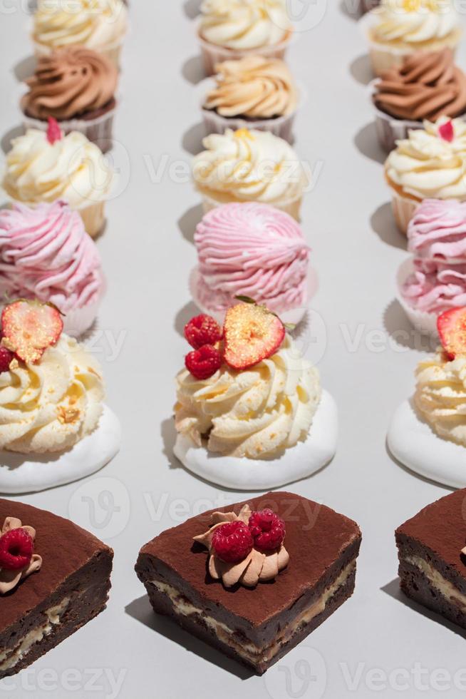 Cakes and muffins in rows on grey background. photo