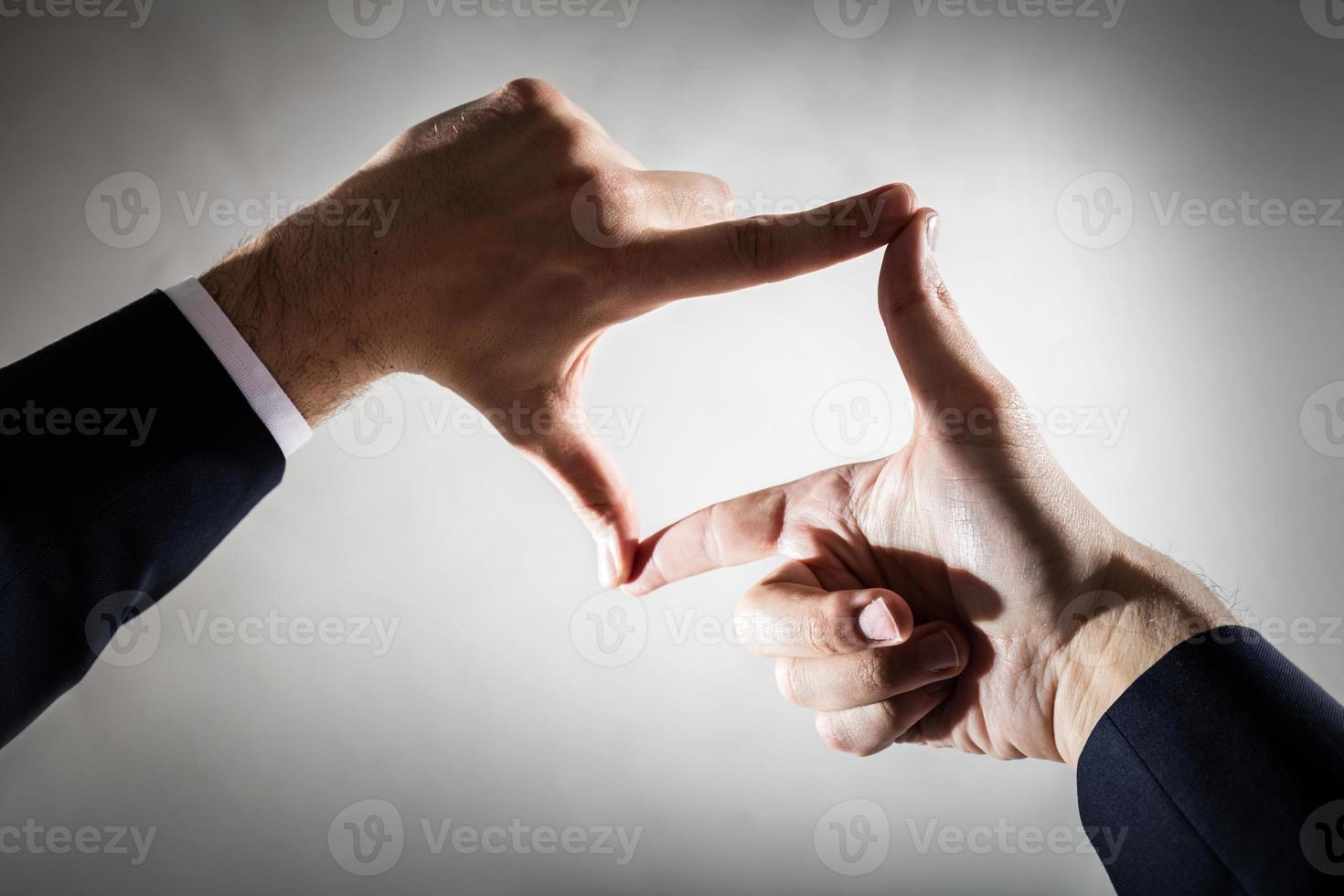 Businessman framing his hands on empty concrete wall photo