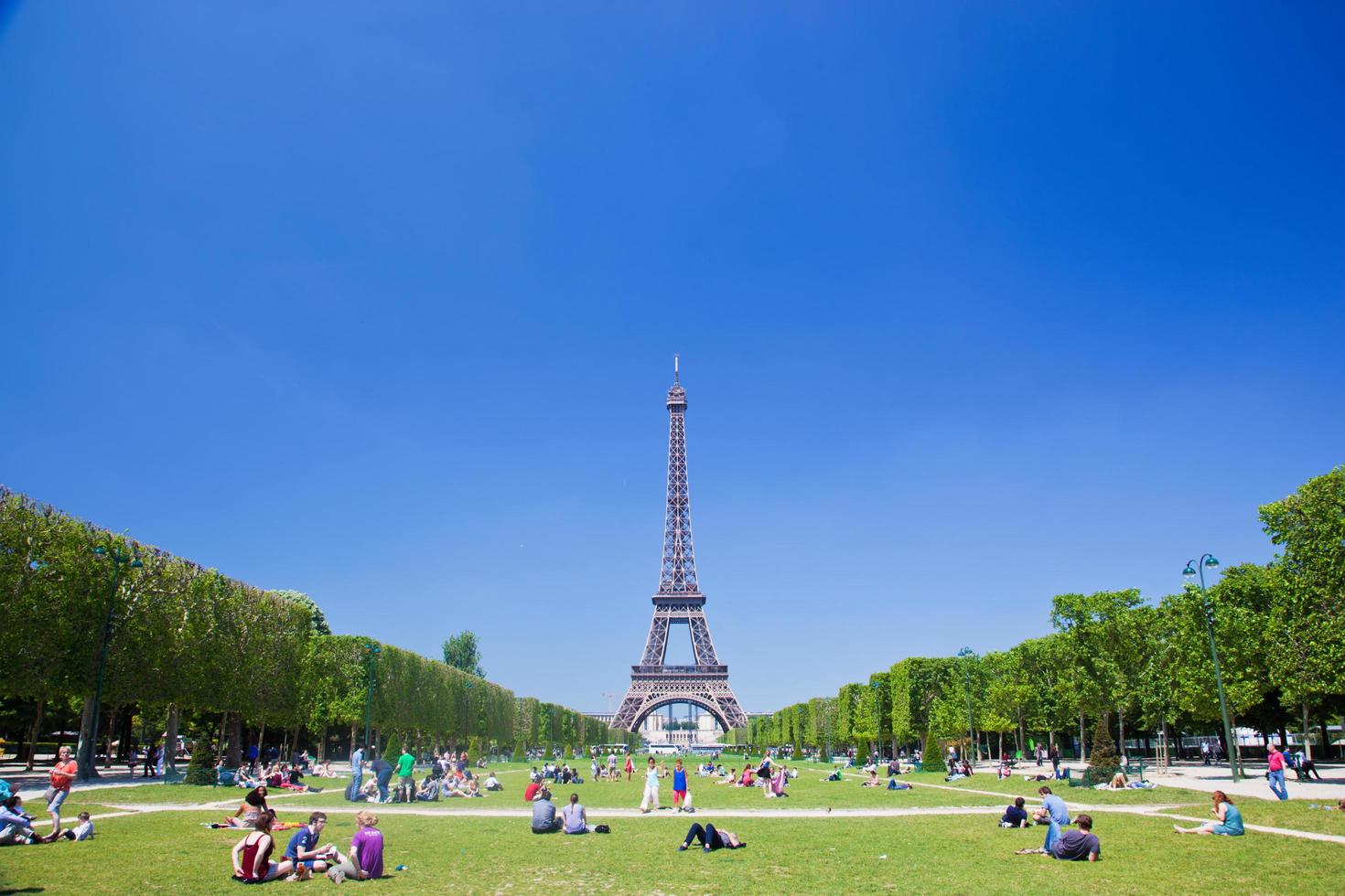 Paris, France, 2022 - Eiffel Tower, Paris, France. Tourists and locals having a break on Champ de Mars photo