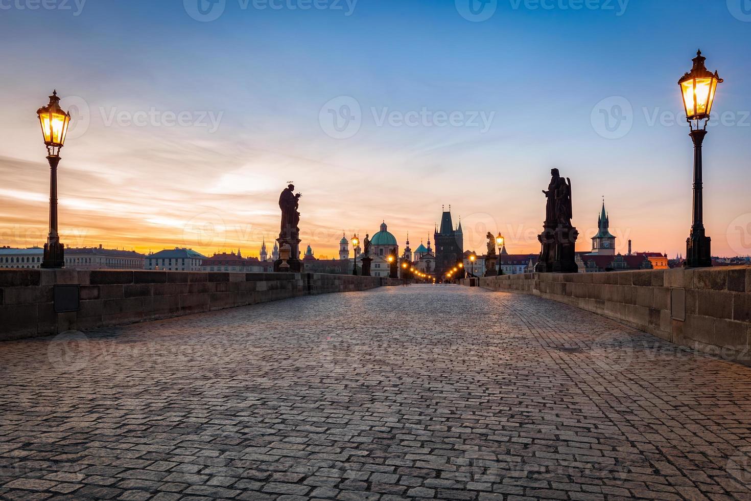 puente de carlos al amanecer, praga, república checa. estatuas dramáticas y torres medievales. foto