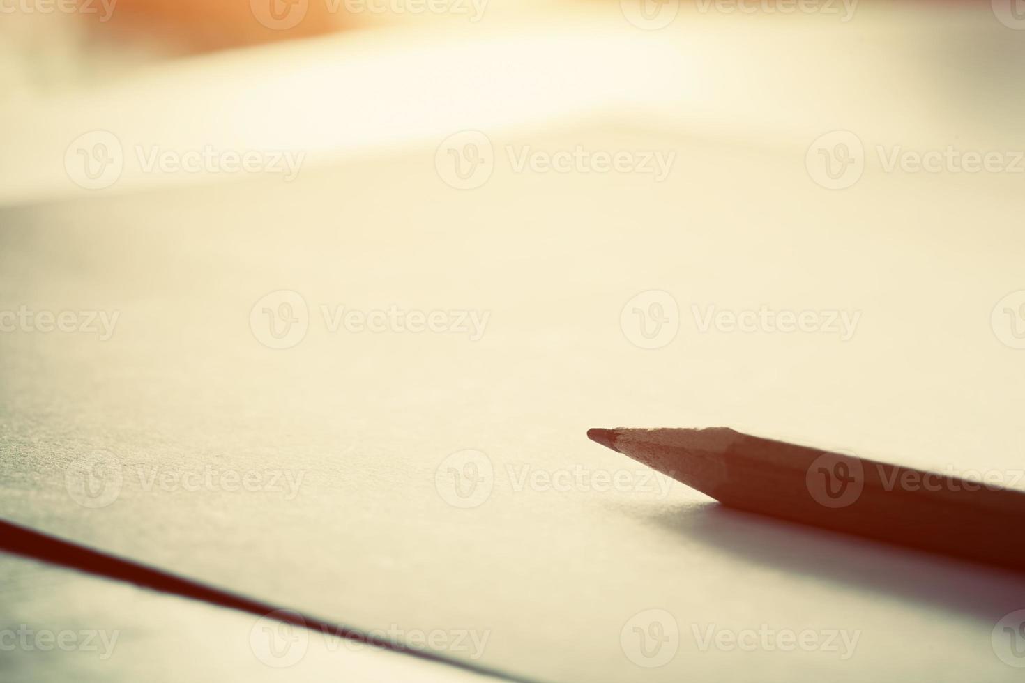 Pencil lying on blank paper in morning light. photo