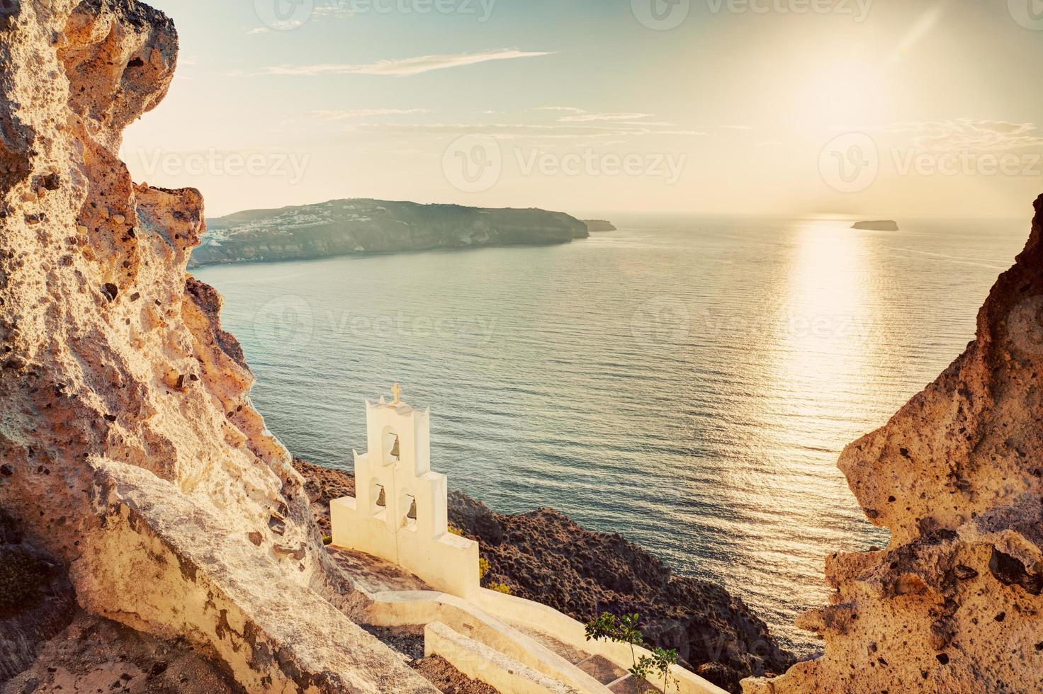 Cliff, volcanic rocks and a traditional chapel on Santorini island, Greece photo