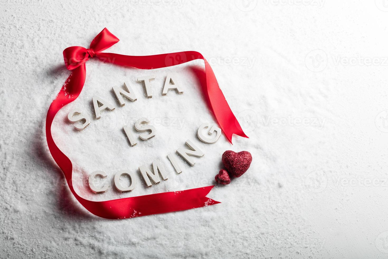 santa viene texto y cinta roja sobre fondo nevado. Navidad. espacio de copia. tradición navideña cristiana. foto