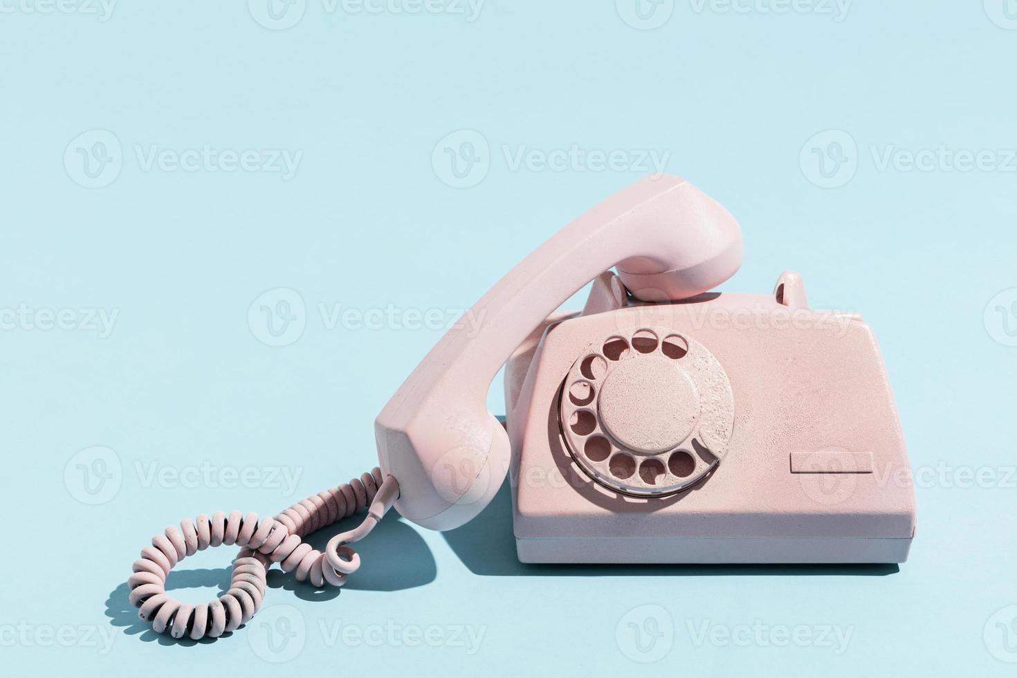 Oldschool pink telephone on a blue background photo