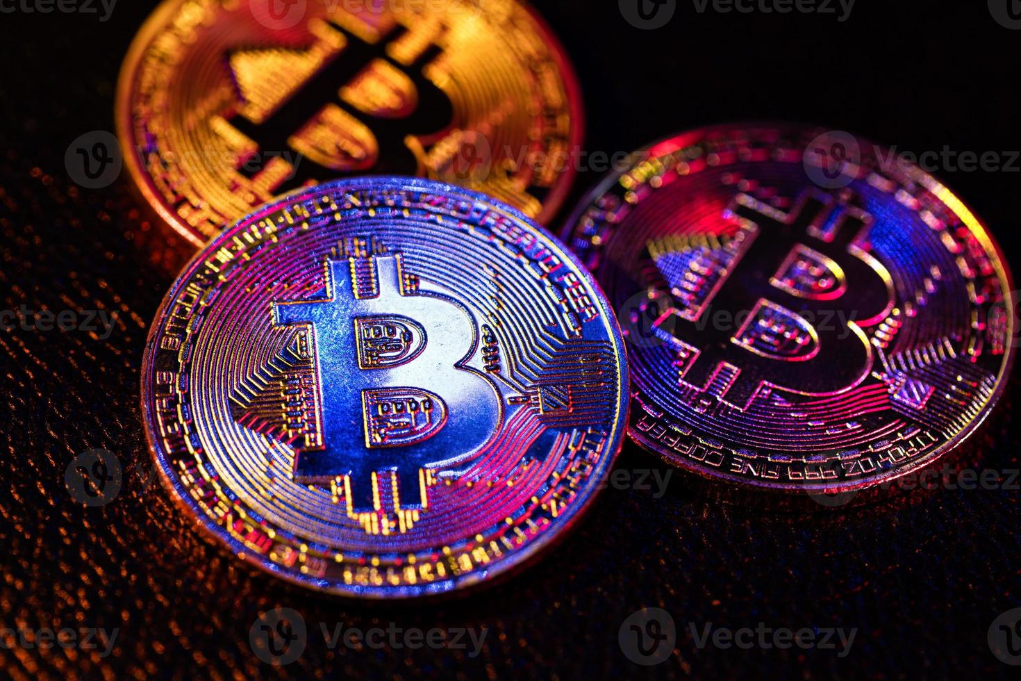 Three coins with bitcoin logo laying on a black background photo