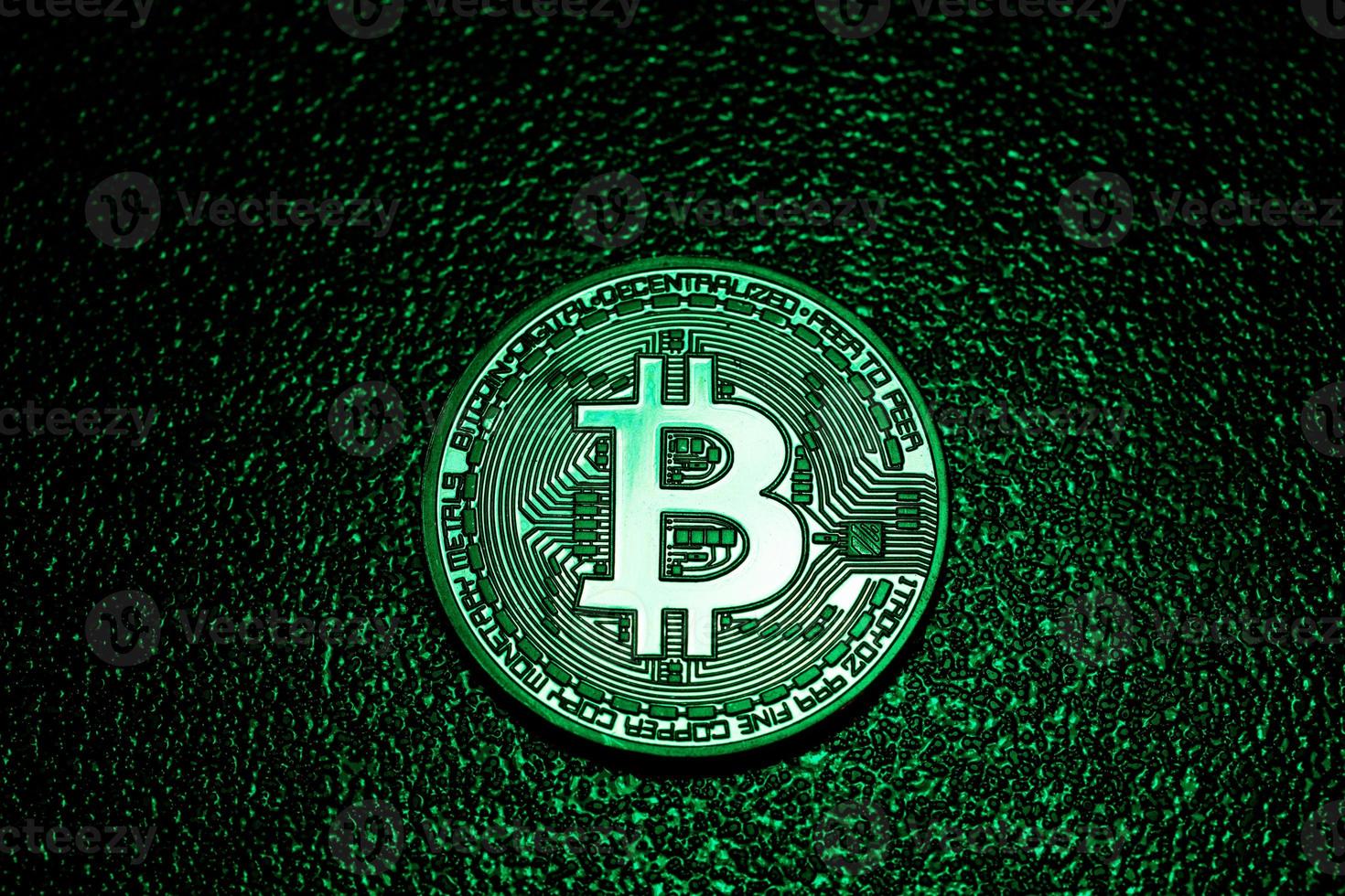 A coin with bitcoin logo in a green lighting. photo