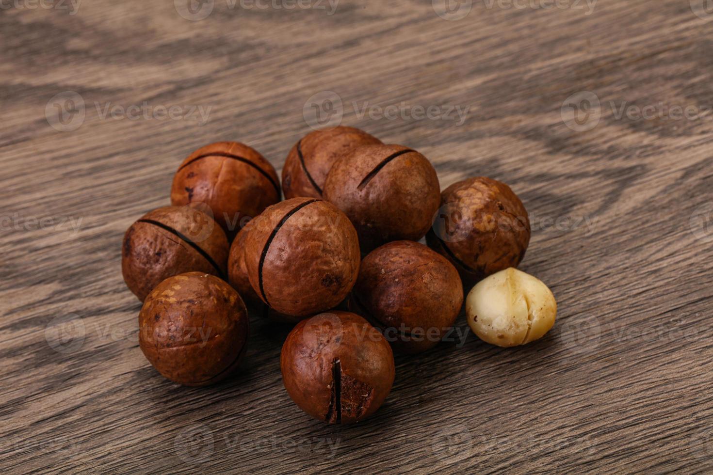 Brown macadamia nut heap over background photo