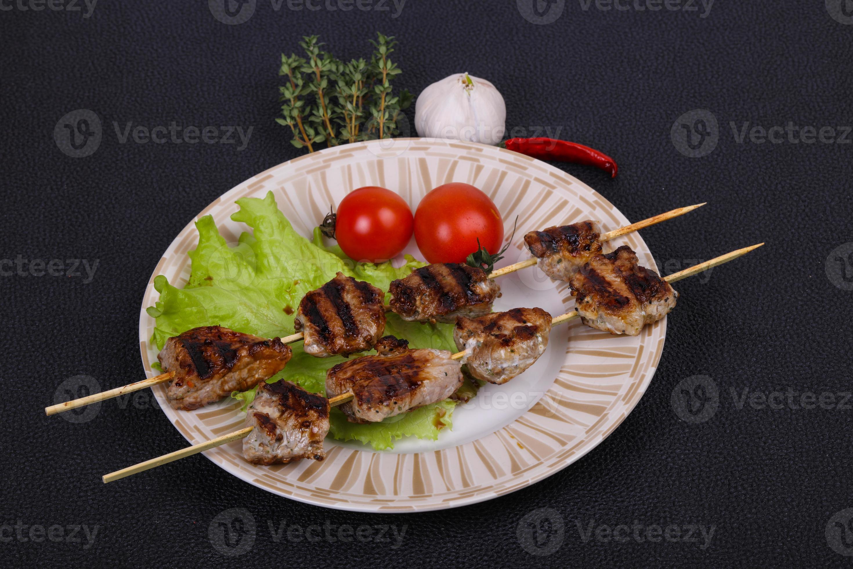 Pork kebab skewers in the plate with salad leaves and tomatoes 7841056
