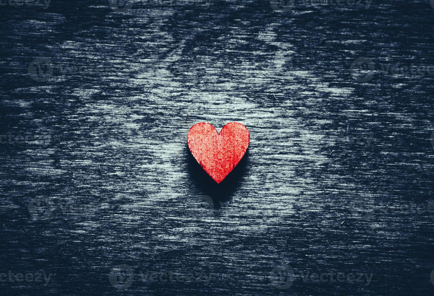 corazón rojo sobre fondo de madera oscura foto
