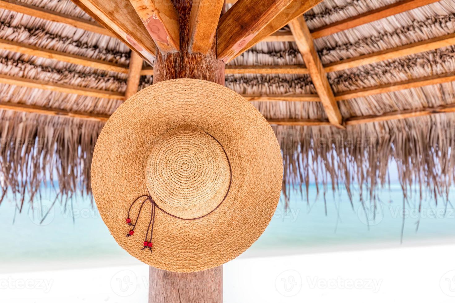 Sun hat hanging on sunshade umbrella on tropical beach. Maldives. photo
