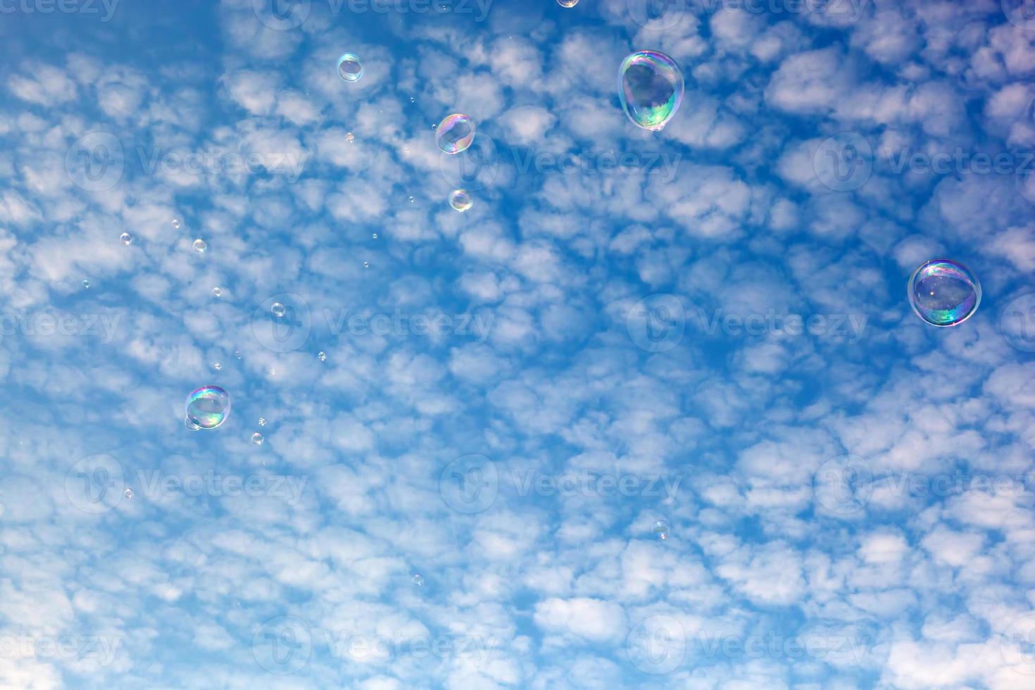 Soap bubbles flying in the air. Puffy clouds sky. photo