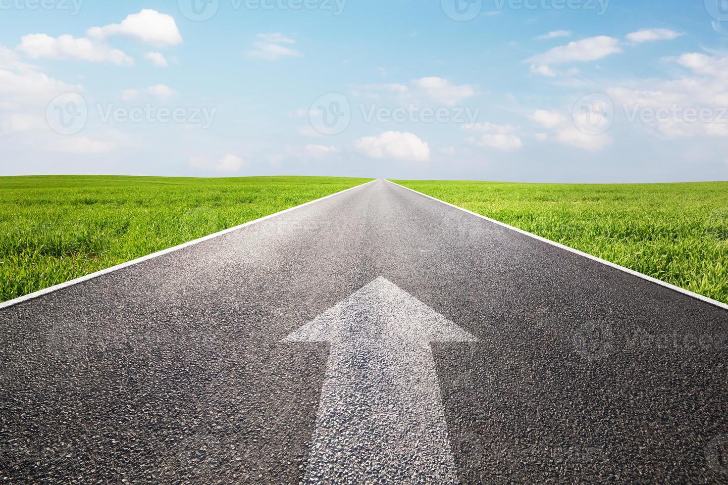 Arrow sign pointing forward on long empty straight road, highway photo