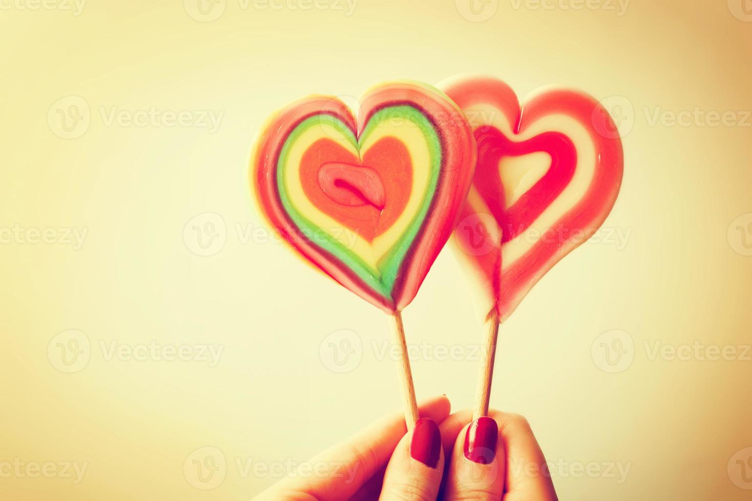 Colorful heart shaped lollipops in woman hand photo