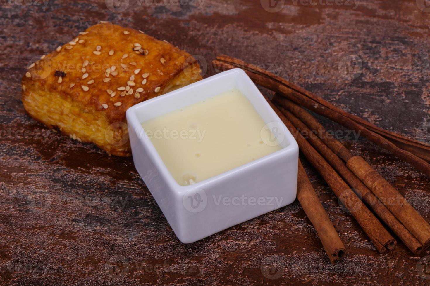 Condenced milk in the bowl with sinnamon and pastry photo