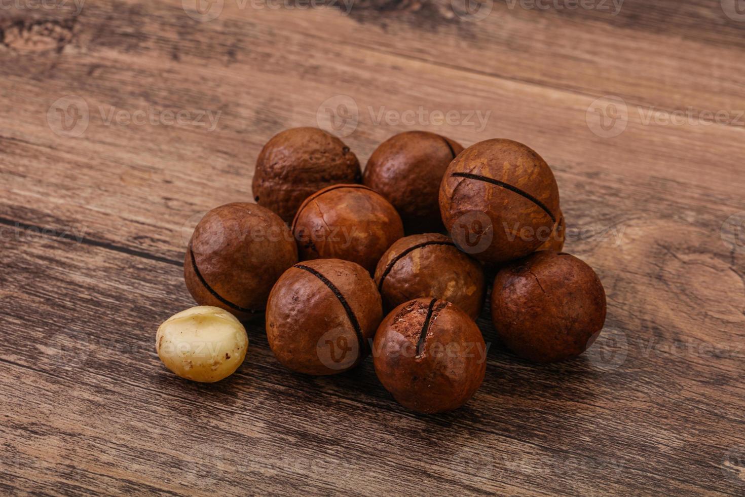 Brown macadamia nut heap over background photo