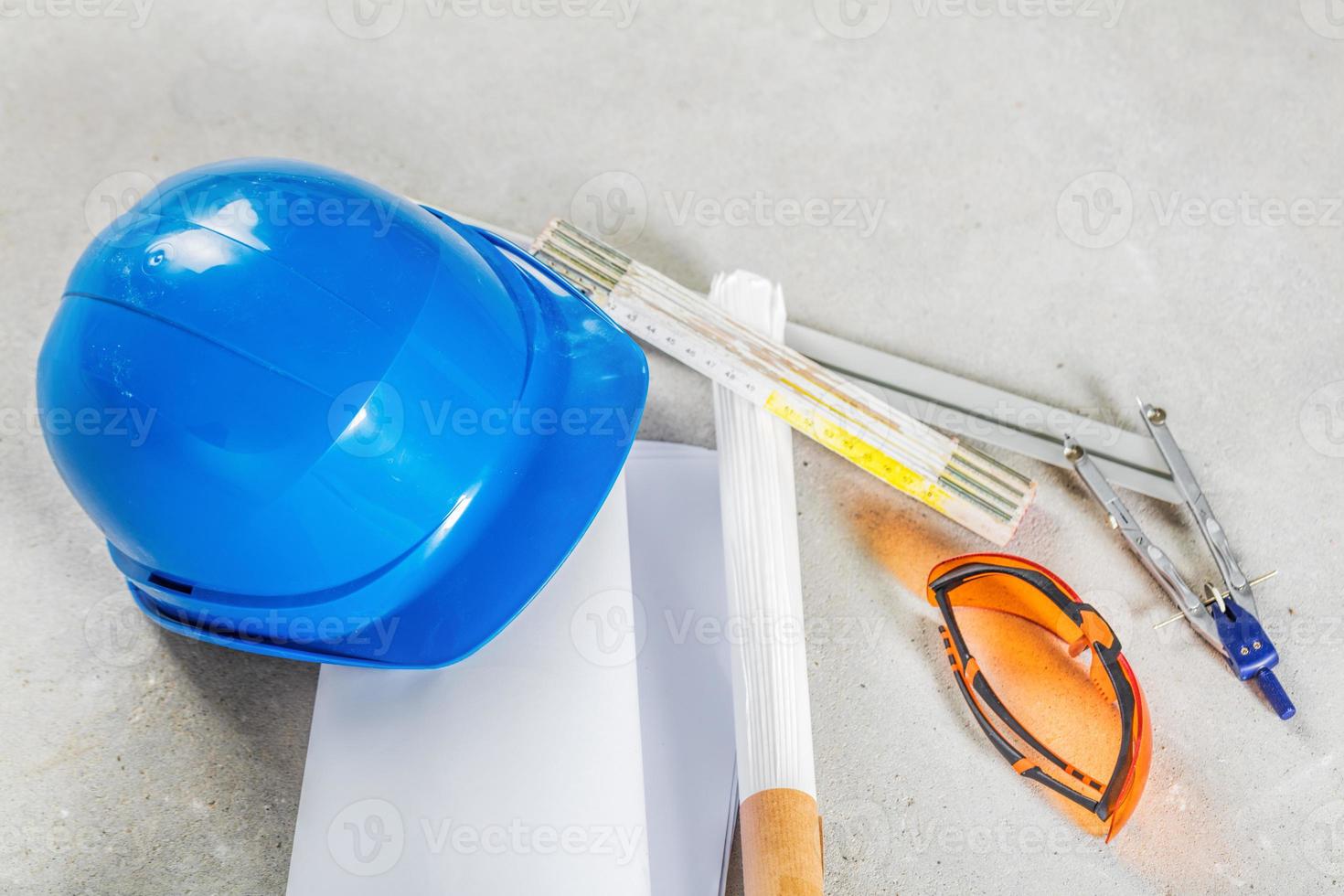 Hard hat, glasses and blueprints at construction site. photo