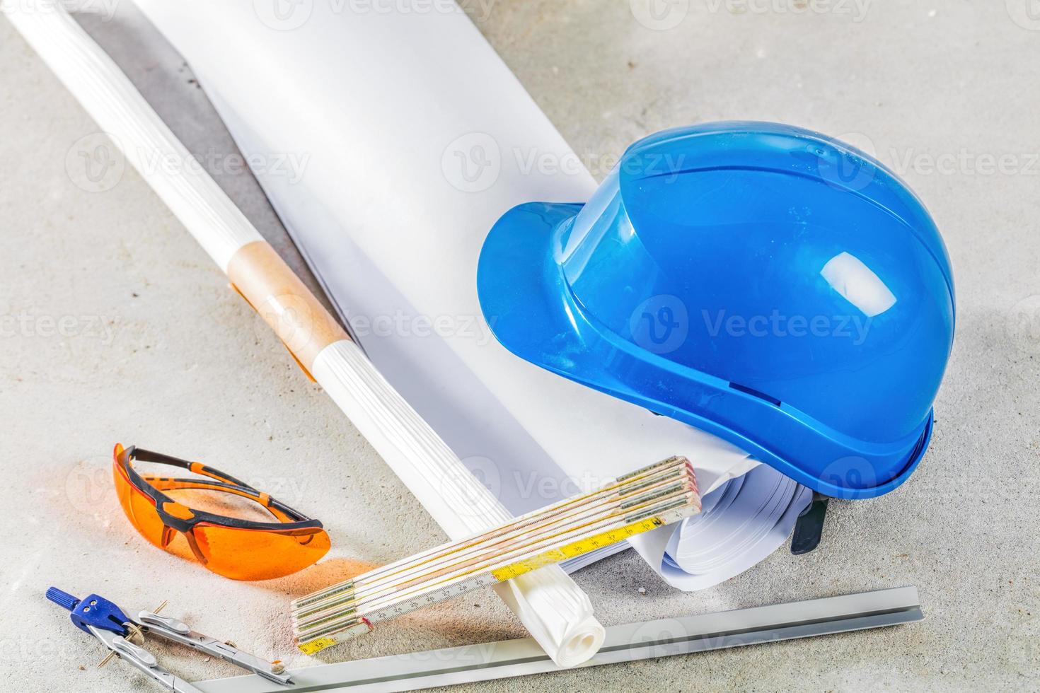 casco, anteojos y planos en el sitio de construcción. foto