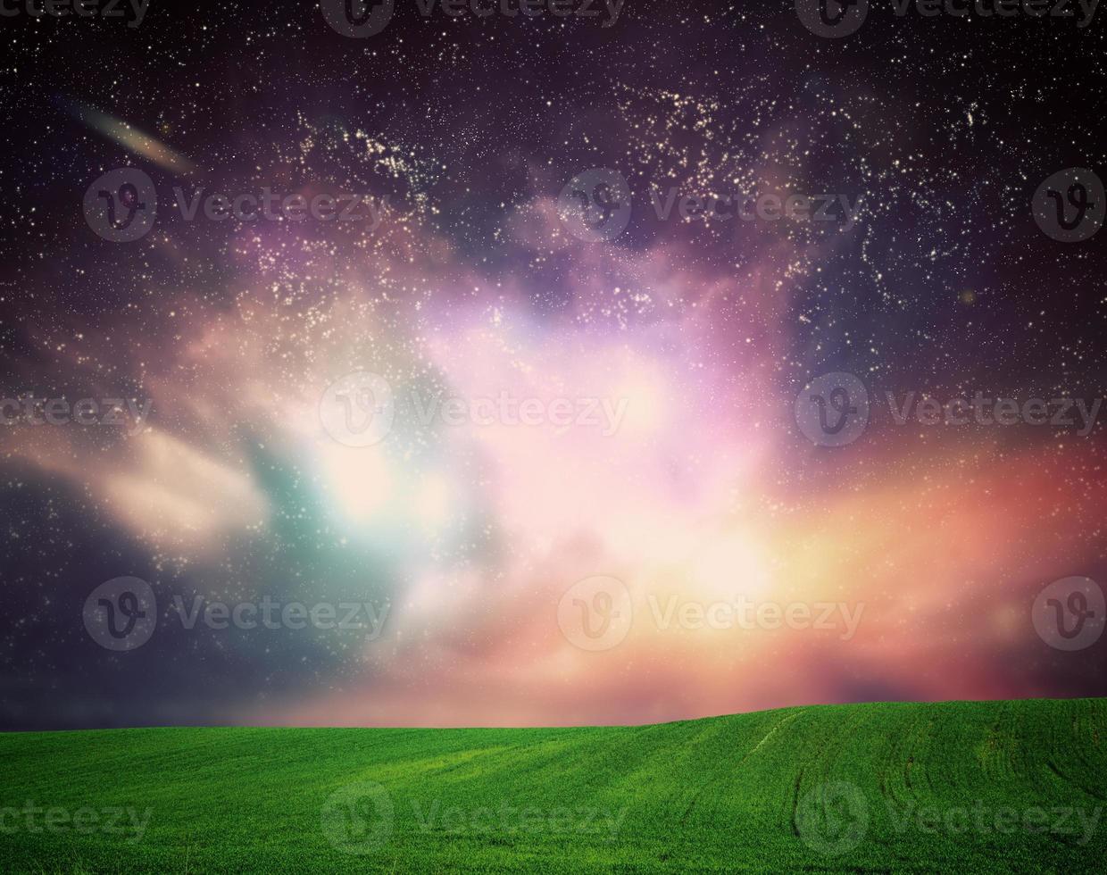 Field of grass under dream galaxy sky, space, glowing stars. photo