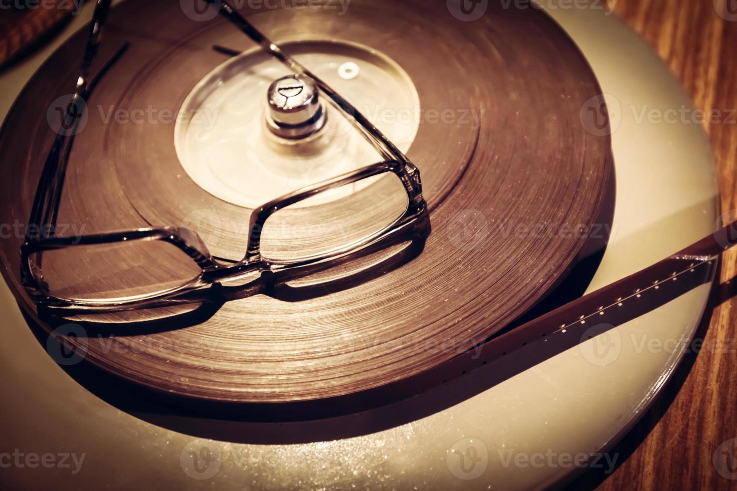 Pair of glasses laying on the top of retro film reel. photo