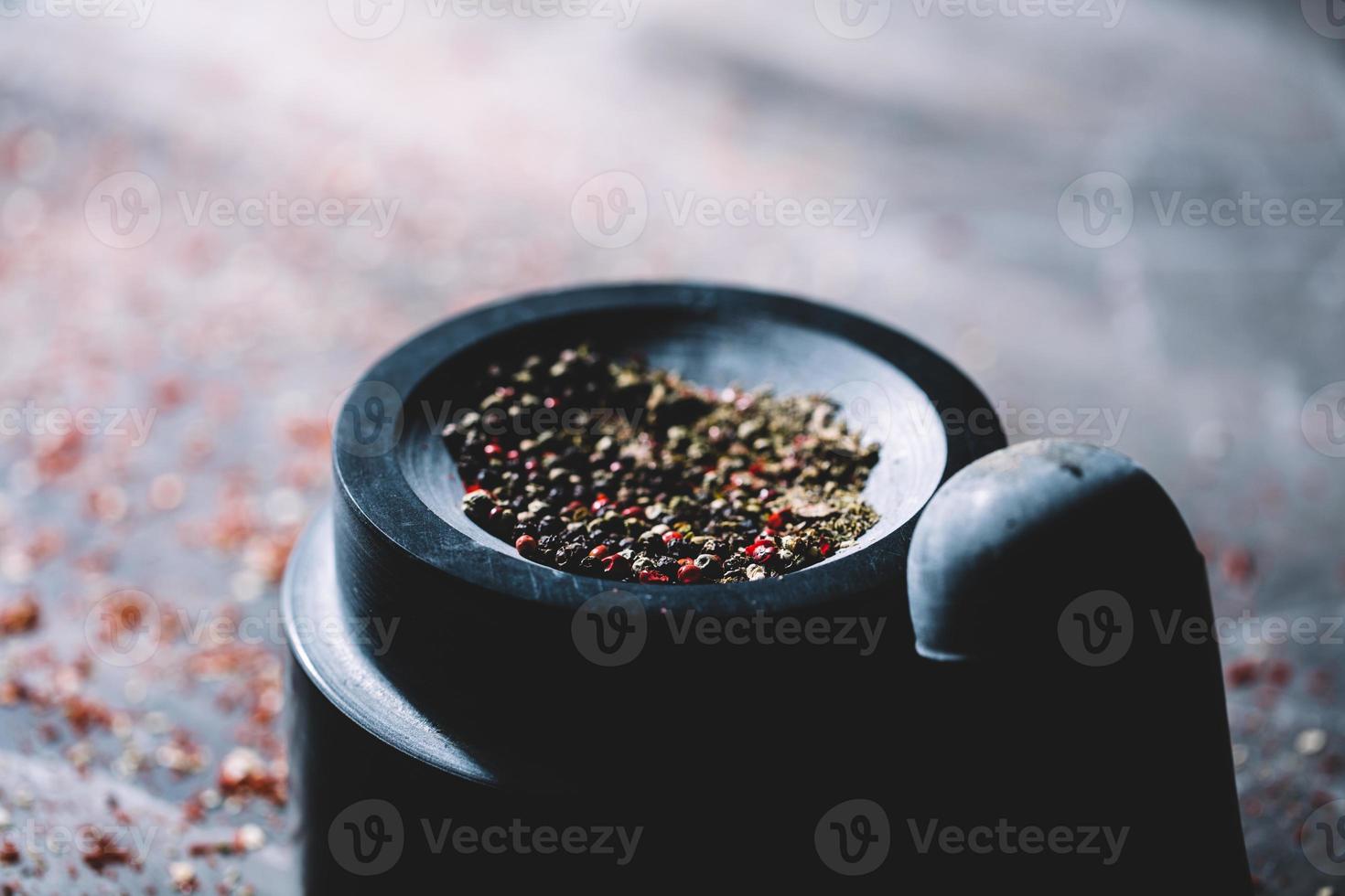 granos de pimienta secos medio machacados colocados en un mortero. foto