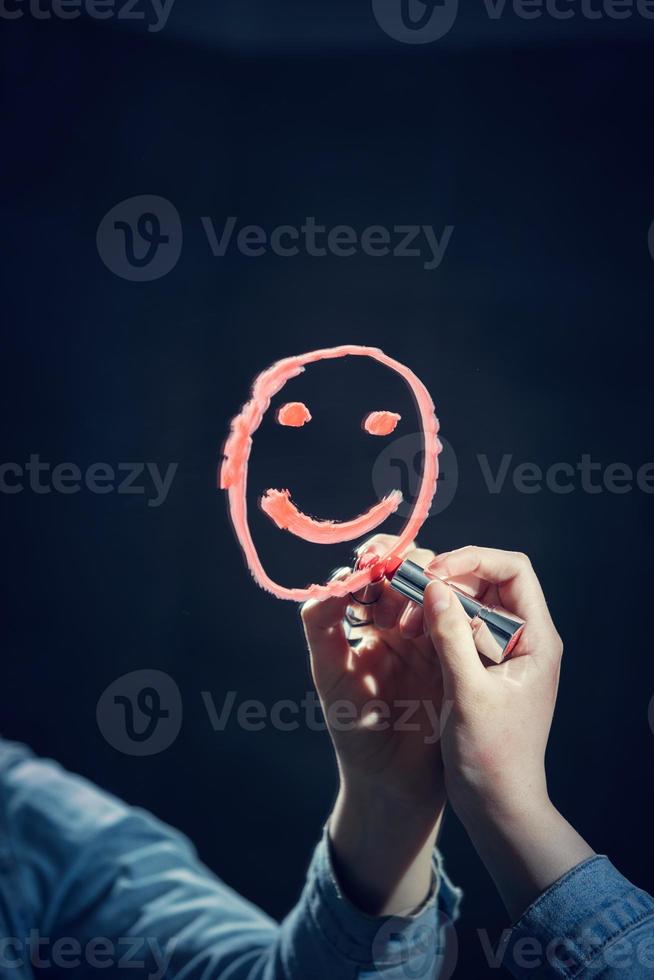 Woman drawing smiley face on a mirror photo