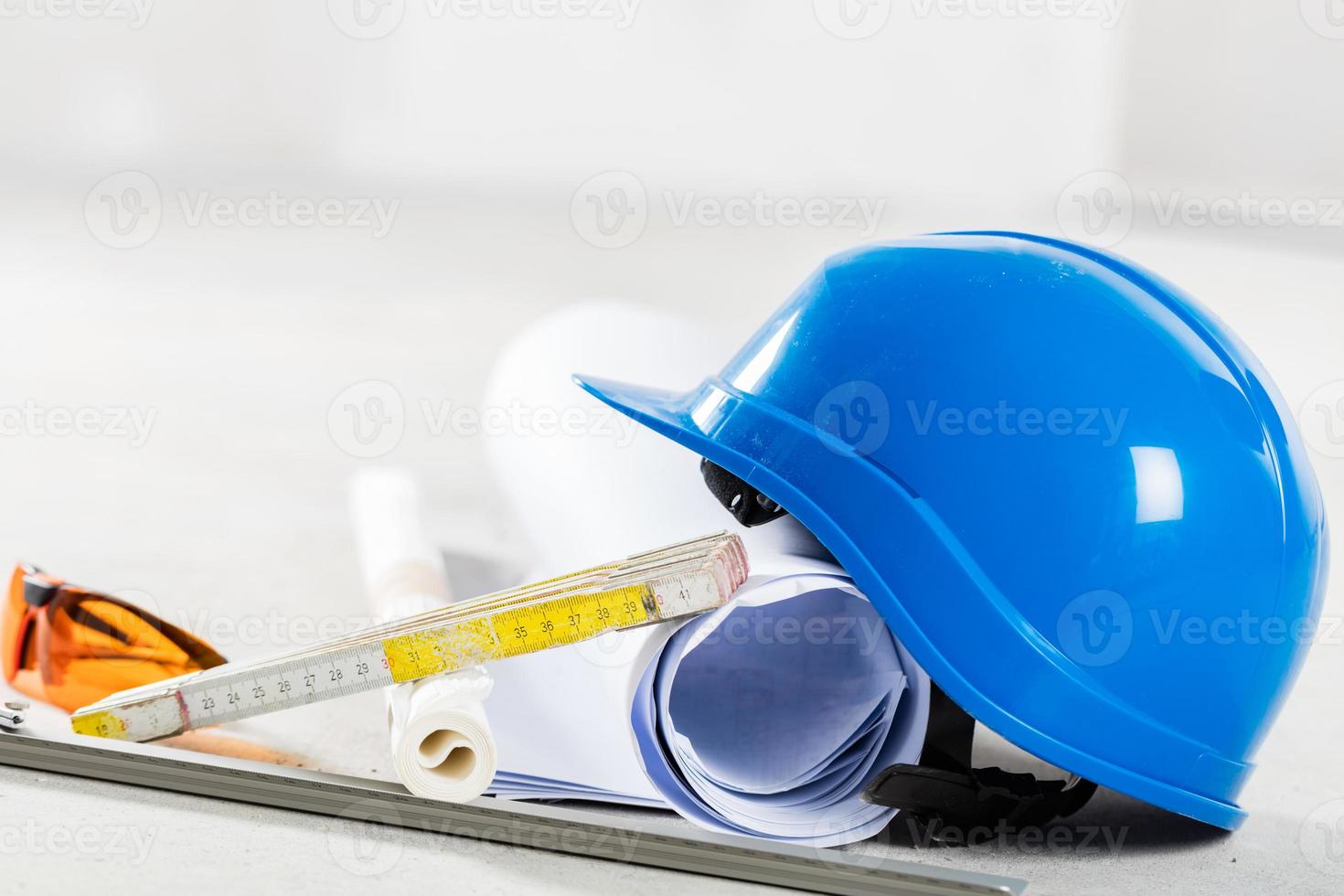 Hard hat, glasses and blueprints at construction site. photo