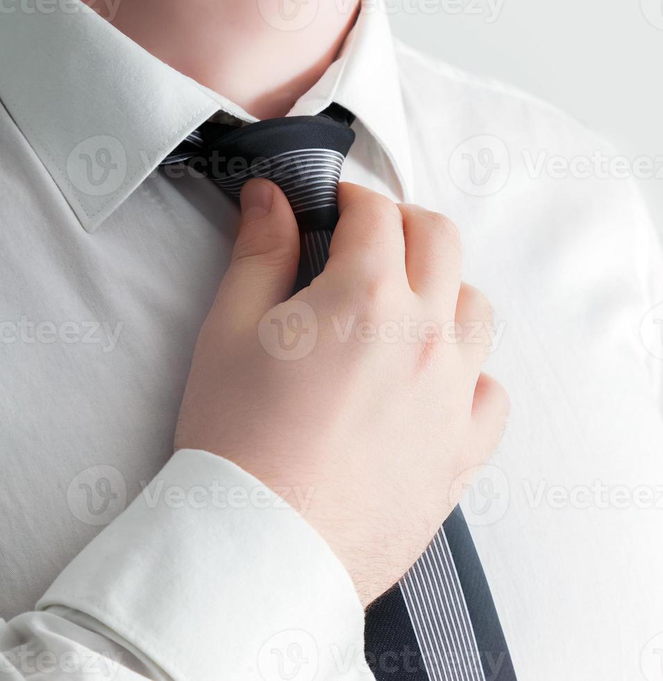 Businessman adjusting his tie, close-up. photo